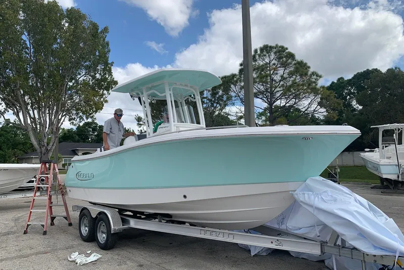 Slide: The Image of 2021 Robalo R230 Center Console boat on trailer, light blue hull, outdoors under cloudy sky. - 6