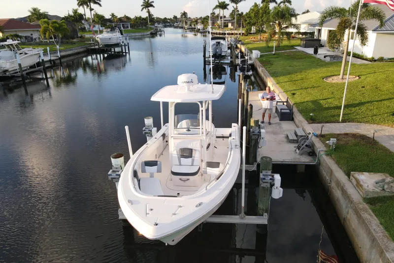 Slide: The Image of 2021 Robalo R230 Center Console boat docked in a scenic canal setting. - 3