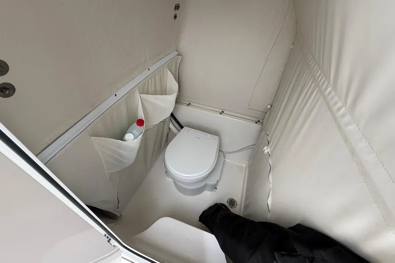 Slide: The Image of 2023 Key West 263 FS boat interior with compact marine toilet and storage pockets. - 19
