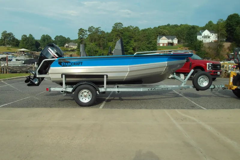 The Image of 2025 Stabicraft 1450 Frontier boat on trailer, parked outdoors near trees and houses. - 1