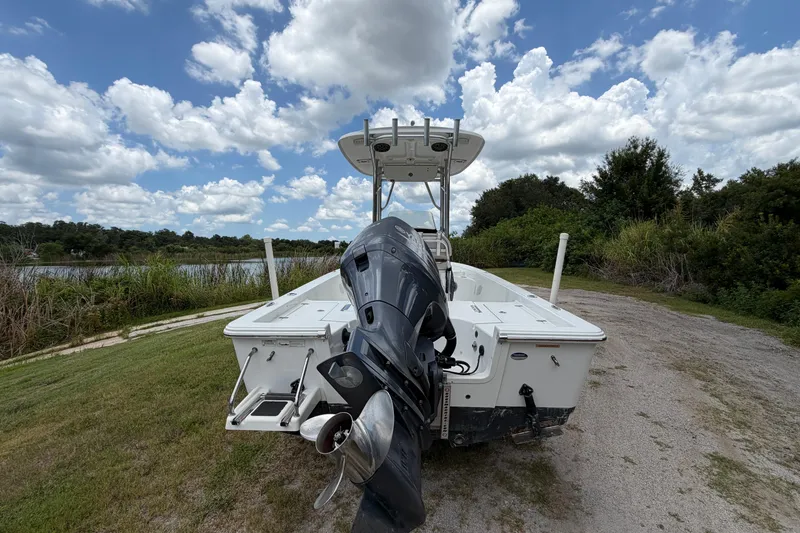 Slide: The Image of 2019 Sportsman Masters 227 Bay Boat with outboard motor on grassy lakeside. - 2