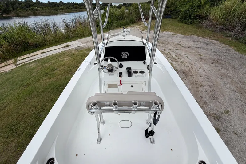 Slide: The Image of 2019 Sportsman Masters 227 Bay Boat interior with steering console, near a serene lakeside. - 4