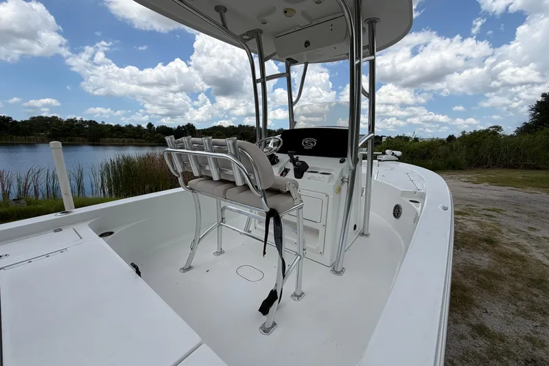 Slide: The Image of 2019 Sportsman Masters 227 Bay Boat interior with seating, console, and scenic lake view. - 14