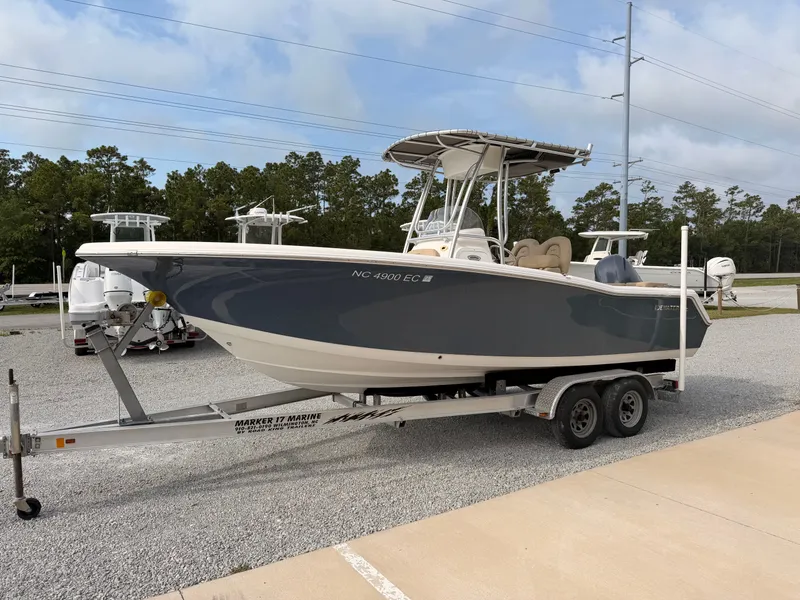 Slide: The Image of A 2016 Tidewater 220 LXF boat on a trailer, surrounded by trees and other boats. - 6