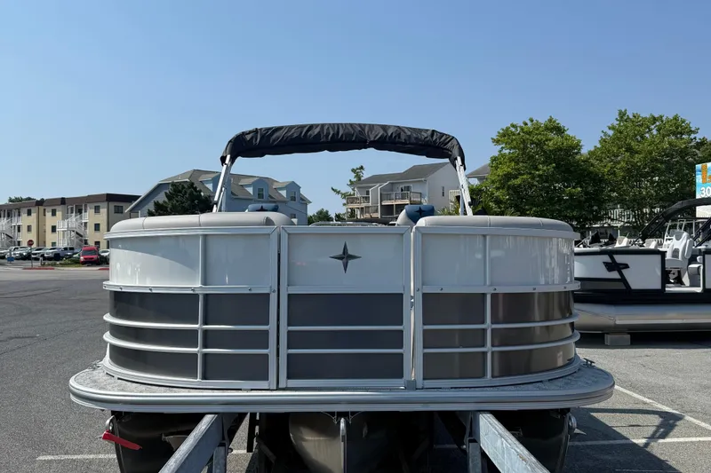 Slide: The Image of 2026 Berkshire 22RFX LE pontoon boat parked in a marina with residential backdrop. - 3