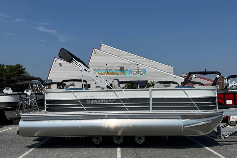 Slide: The Image of 2026 Berkshire 22RFX LE pontoon boat parked outdoors under clear blue sky. - 1