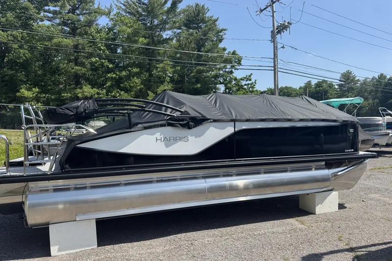 The Image of 2027 Harris Sunliner 230 pontoon boat with cover, parked outdoors on a sunny day. - 1