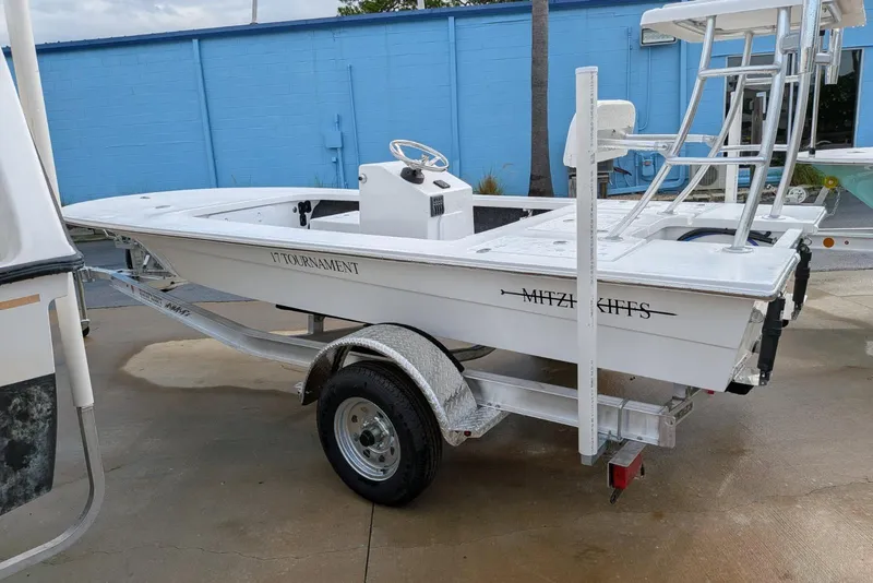 Slide: The Image of 2026 Mitzi Skiffs 17 Tournament boat on trailer, parked outdoors near blue wall. - 1