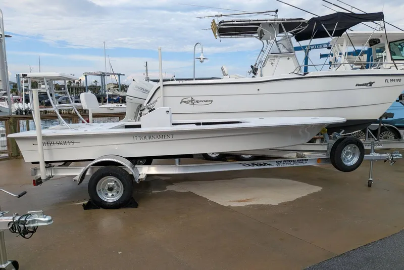 Slide: The Image of 2026 Mitzi Skiffs 17 Tournament boat on trailer, dockside with other boats in background. - 2