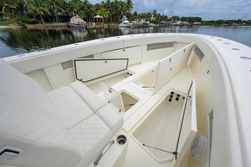 Slide: The Image of 2016 SeaVee 390Z boat interior with open storage compartments, docked by a lush shoreline. - 13