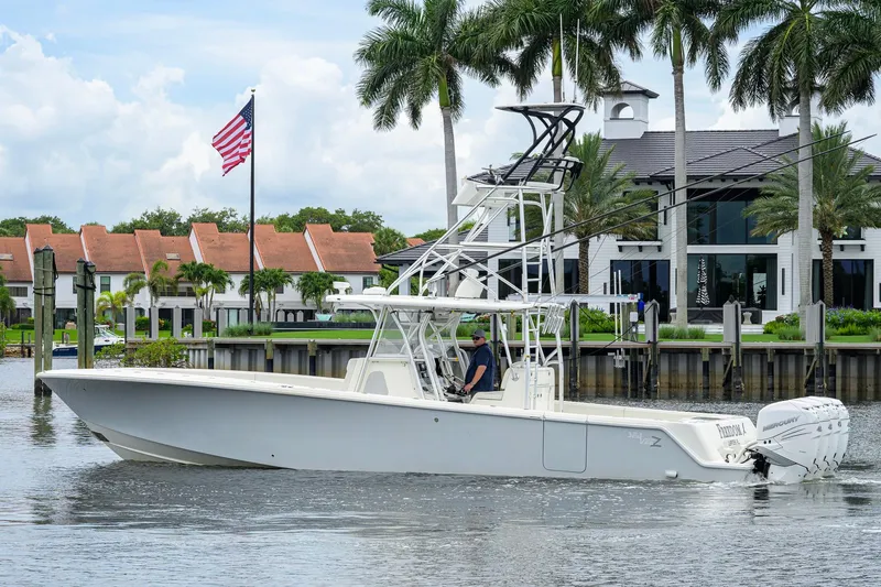 Slide: The Image of 2016 SeaVee 390Z boat cruising near waterfront homes with palm trees and American flag. - 65