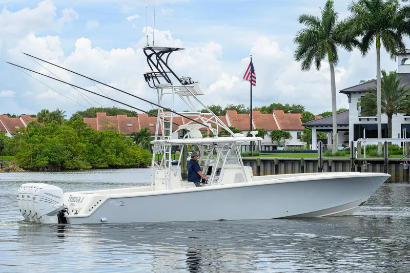 Slide: The Image of 2016 SeaVee 390Z boat cruising on a calm waterway with palm trees and houses in the background. - 69