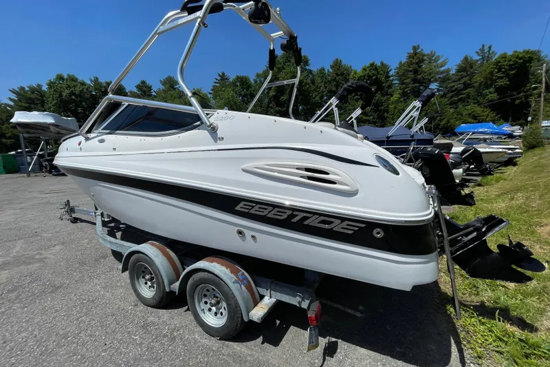 Slide: The Image of 2005 Ebbtide 2200 Bow Rider boat on trailer, parked outdoors under clear blue sky. - 8