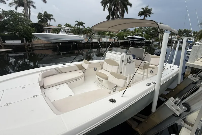 Slide: The Image of 2016 Robalo 246 Cayman boat docked, featuring spacious seating and canopy, surrounded by palm trees. - 2
