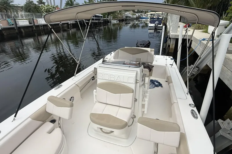 Slide: The Image of 2016 Robalo 246 Cayman boat with seating and canopy, docked by a calm waterway. - 7