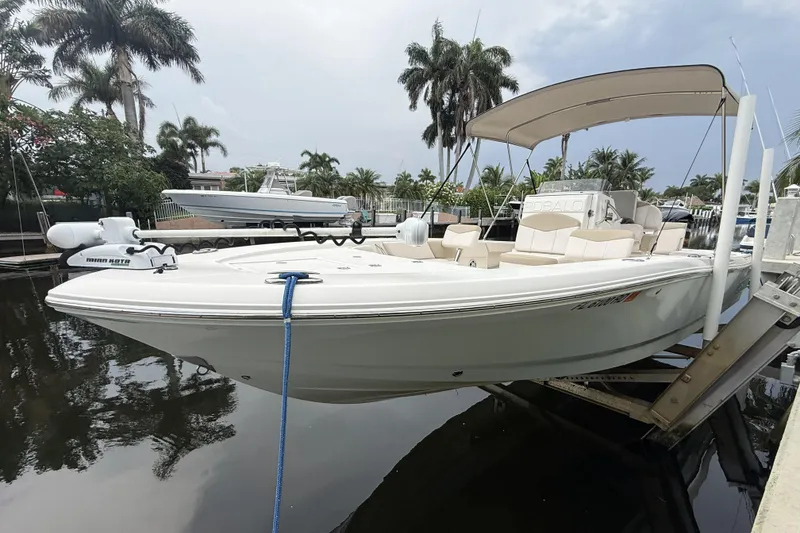 The Image of 2016 Robalo 246 Cayman boat docked with canopy, surrounded by palm trees. - 0