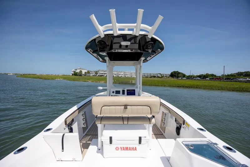 Slide: The Image of 2023 Yamaha Boats 222 FSH Sport E on calm water, showcasing spacious deck and seating. - 8