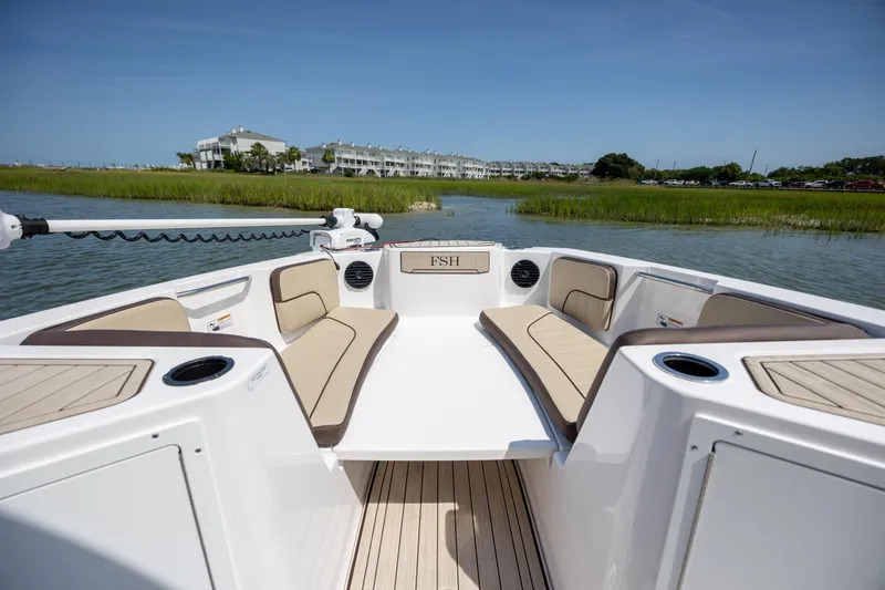 Slide: The Image of 2023 Yamaha Boats 222 FSH Sport E interior with seating, on a scenic waterway. - 16