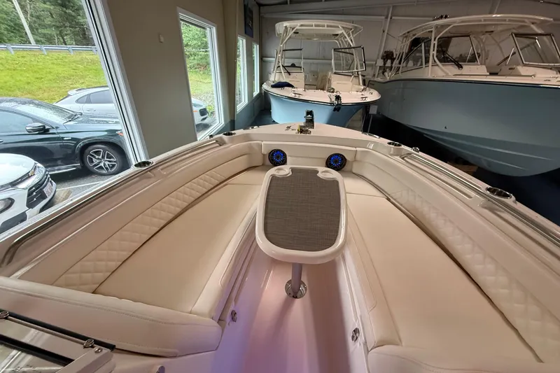 Slide: The Image of 2026 Grady-White Freedom 235 boat interior with luxurious seating and table in showroom. - 13