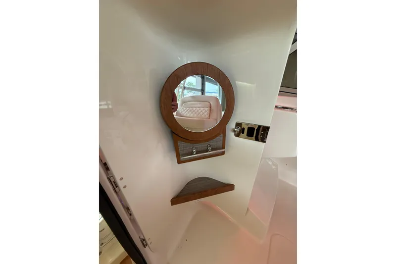 Slide: The Image of Interior of 2026 Grady-White Freedom 235 boat with round mirror and wooden accents. - 30