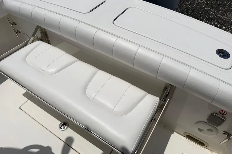 Slide: The Image of 2015 Regulator 23 Center Console boat with white cushioned seating and storage compartment. - 7