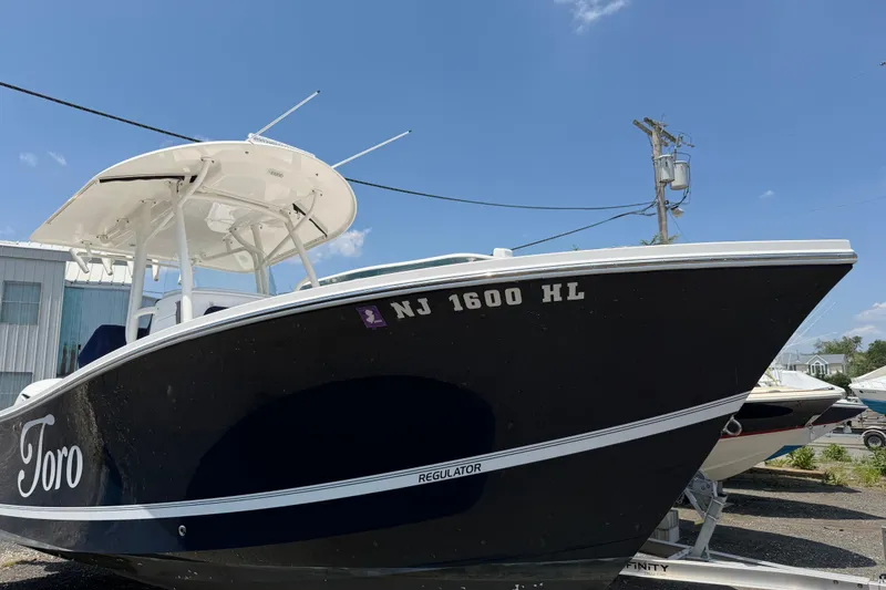 Slide: The Image of 2015 Regulator 23 Center Console boat on trailer, blue hull, clear sky background. - 4