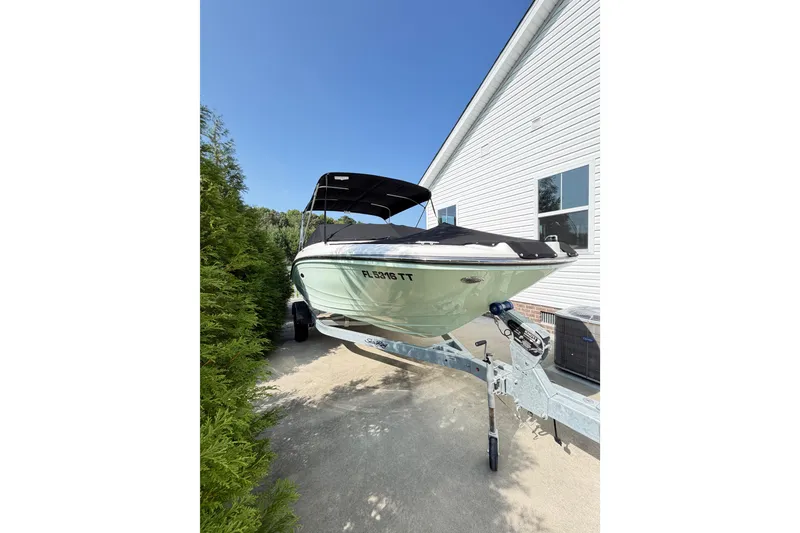 Slide: The Image of 2024 Sea Ray SPX 190 Outboard boat on trailer, parked beside a white building. - 1