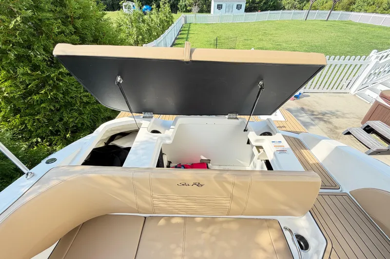 Slide: The Image of 2024 Sea Ray SPX 190 Outboard boat with open storage compartment, beige seating, and wooden deck. - 40