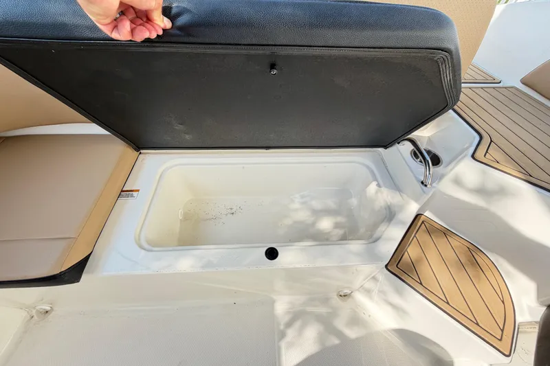 Slide: The Image of 2024 Sea Ray SPX 190 Outboard boat storage compartment with open lid and seating area. - 32