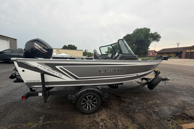 Slide: The Image of 2025 Lund 1775 Impact XS Sport boat on trailer, featuring Mercury engine, parked outdoors. - 3