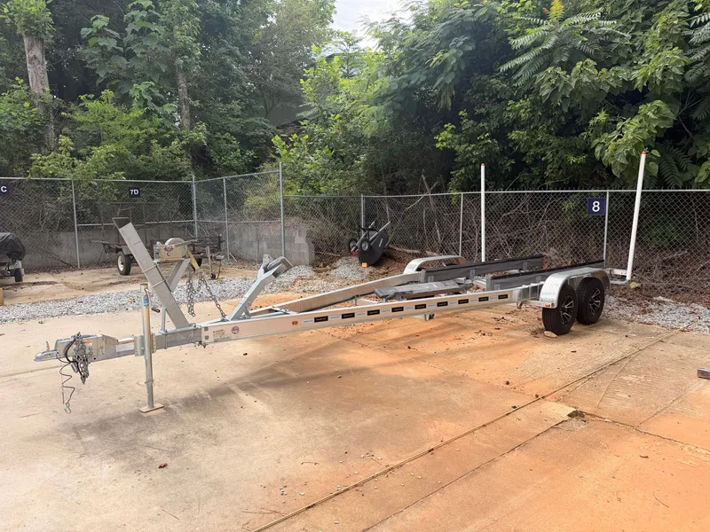 Slide: The Image of An empty boat trailer sits on a concrete lot, surrounded by trees and a chain-link fence. - 41