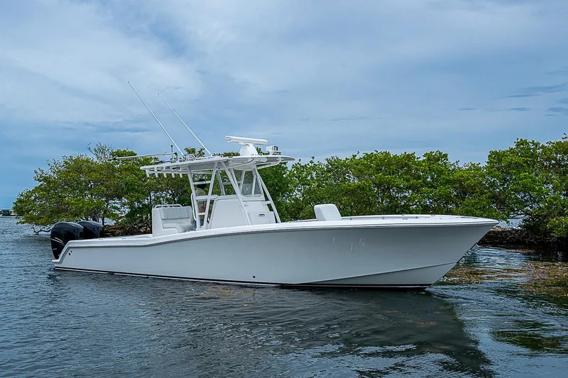 Slide: The Image of 2018 Invincible 33 Open Fisherman boat on calm water near lush greenery. - 38