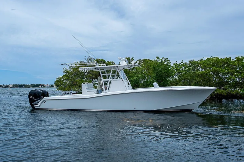 Slide: The Image of 2018 Invincible 33 Open Fisherman boat on calm water, surrounded by lush greenery. - 40
