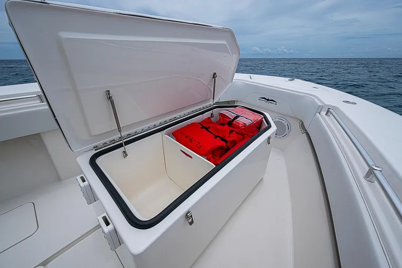 Slide: The Image of Open storage compartment on 2018 Invincible 33 Open Fisherman boat with red life jackets. - 18