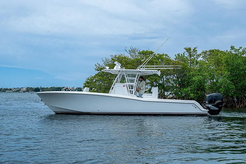 Slide: The Image of 2018 Invincible 33 Open Fisherman boat on calm water near lush greenery. - 48