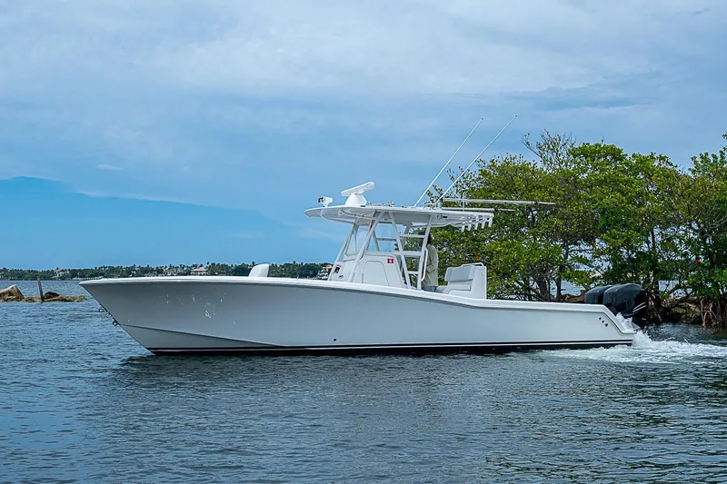 Slide: The Image of 2018 Invincible 33 Open Fisherman boat cruising on calm waters near lush greenery. - 49