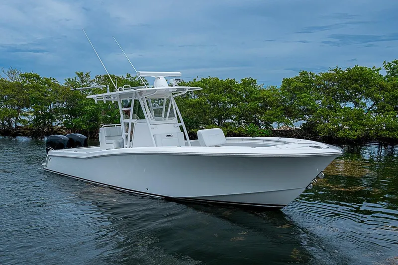 The Image of 2018 Invincible 33 Open Fisherman boat on calm water, surrounded by lush greenery. - 1