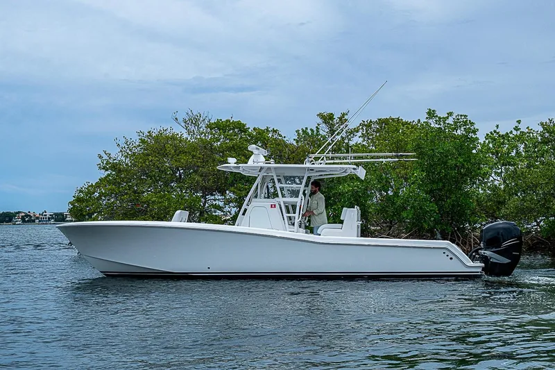Slide: The Image of 2018 Invincible 33 Open Fisherman boat on water near lush greenery. - 47