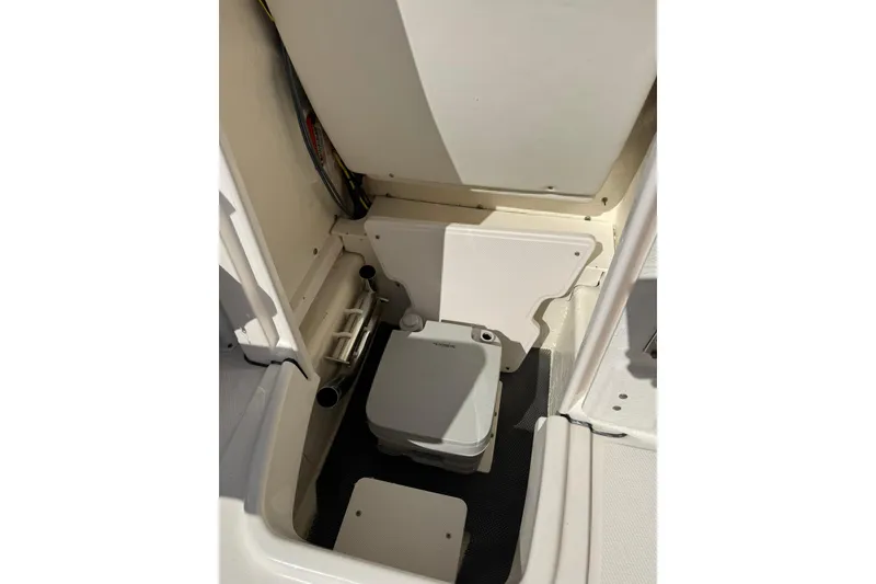 Slide: The Image of 2022 Robalo R200 Center Console boat interior with storage compartment and portable toilet. - 18