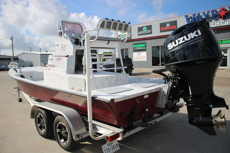 Slide: The Image of 2022 Shoalwater 20' Catamaran with Suzuki outboard motor, parked at dealership. - 2