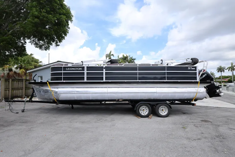 Slide: The Image of 2021 Lexington 525 Series 5 pontoon boat on trailer, parked outdoors. - 2