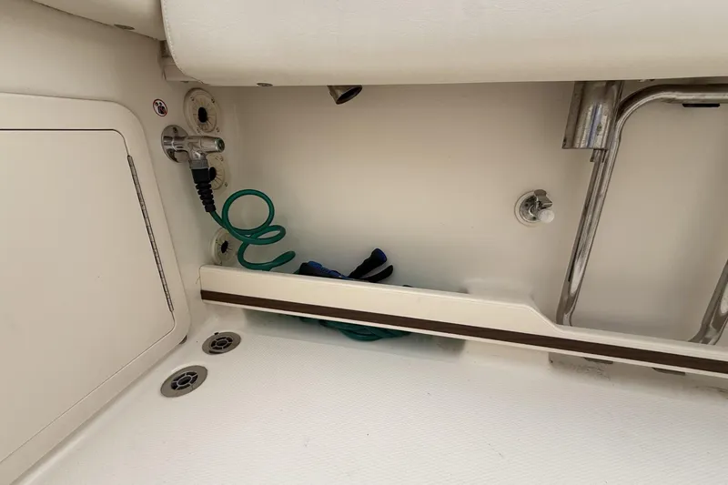 Slide: The Image of 2020 Grady-White Fisherman 257 boat interior, featuring storage compartment and coiled hose. - 21