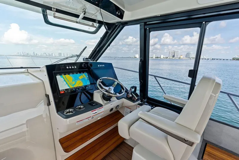 Slide: The Image of Helm of 2024 Boston Whaler 405 Conquest with navigation display, overlooking ocean and city skyline. - 32