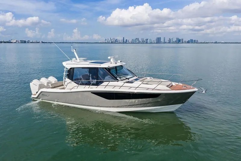 Slide: The Image of 2024 Boston Whaler 405 Conquest cruising on calm waters with city skyline backdrop. - 10