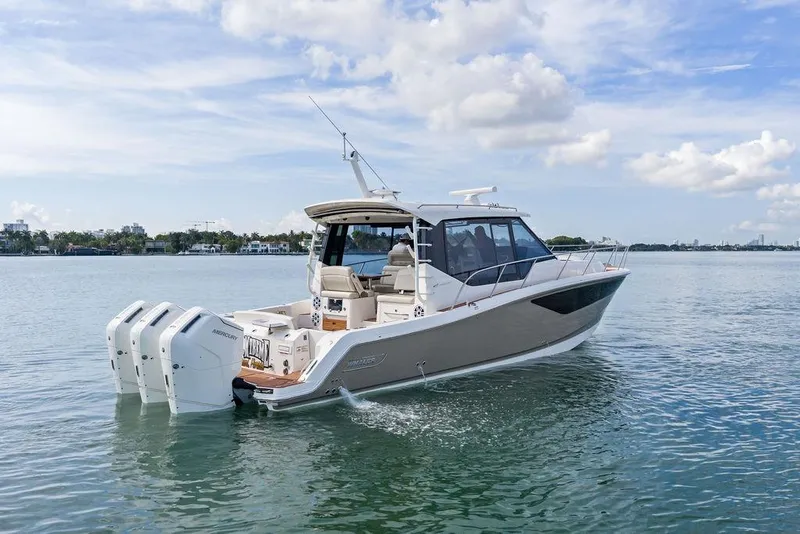 Slide: The Image of 2024 Boston Whaler 405 Conquest boat cruising on calm waters under a partly cloudy sky. - 7