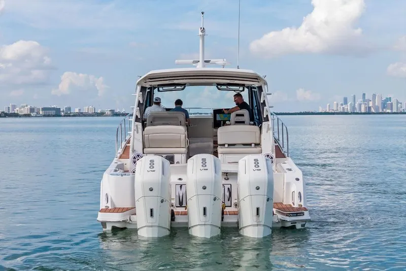 Slide: The Image of 2024 Boston Whaler 405 Conquest cruising on calm waters with city skyline backdrop. - 6