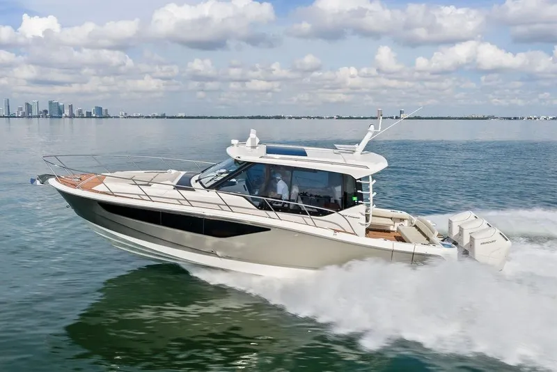 The Image of 2024 Boston Whaler 405 Conquest cruising on open water with city skyline backdrop. - 1
