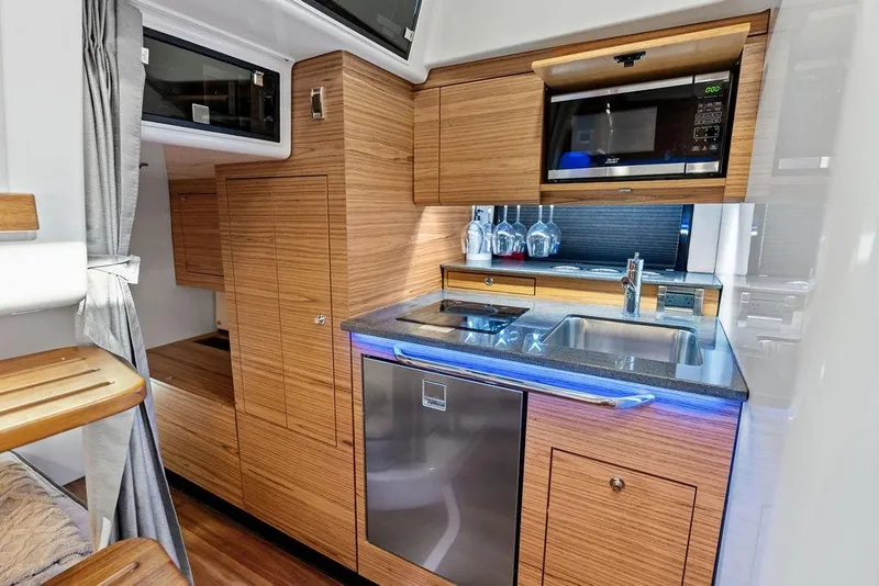 Slide: The Image of Modern kitchen interior of 2024 Boston Whaler 405 Conquest boat, featuring wood cabinetry and stainless appliances. - 54