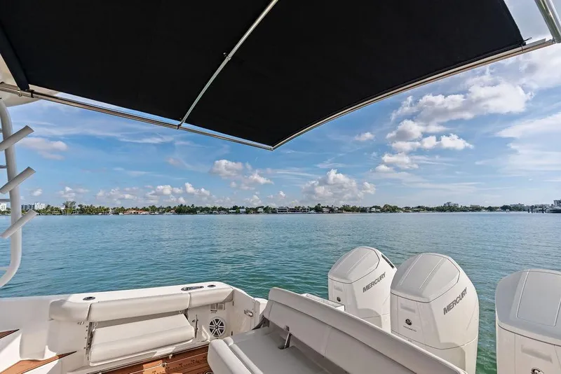 Slide: The Image of 2024 Boston Whaler 405 Conquest boat with Mercury engines on a serene water backdrop. - 48