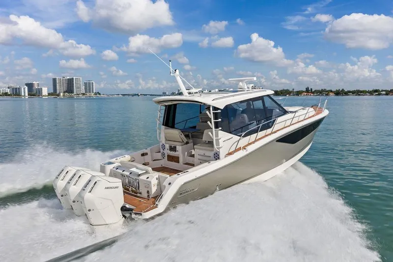 Slide: The Image of 2024 Boston Whaler 405 Conquest cruising on a sunny day with city skyline backdrop. - 15